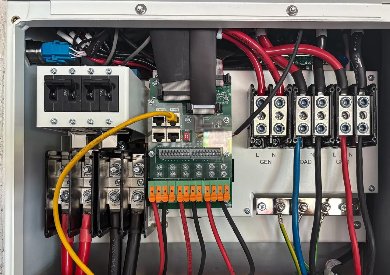 Intérieur d'un coffret électrique avec bornes, câbles rouges et noirs et disjoncteurs